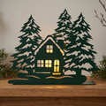 Dark green Cabin in the Woods metal candle luminary with warm window glow displayed on a mantel